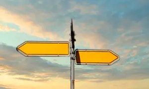 Doble señalización amarilla vacía, como **leading indicators** de un camino a seguir, contra un cielo nublado.