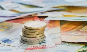 Pila de monedas de euro sobre billetes. Cada moneda cuenta diferentes opiniones sobre el valor del dinero.