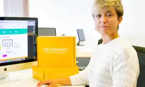 Diana de Arias, rodeada de cajas de "Decedario", un juego para estimulación cognitiva.