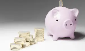 Cerdo rosa con monedas apiladas, simbolizando el inicio de emprender sin dinero y el ahorro para un futuro próspero.