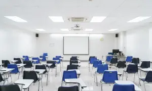 Aula vacía con sillas azules y negras, mesas y proyector. Ideal para pensar en los requisitos para abrir una academia de formación no reglada.