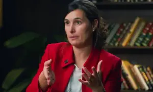 Andrea, del club de inversión, comparte sus opiniones con gestos enfáticos. Detrás, estanterías llenas de libros.