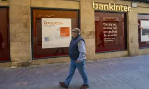 Un hombre camina frente a una sucursal de Bankinter. Las reseñas de Bankinter destacan su compromiso con la sostenibilidad.