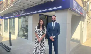 Dos empleados sonríen frente a la sucursal de Banca Pueyo. Las opiniones sobre Banca Pueyo son positivas.