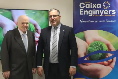 Dos hombres posan frente a un cartel de Caixa Enginyers. Las opiniones sobre la entidad son positivas, destacando su enfoque en "humanizar las finanzas".