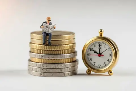 Hombrecito sentado en monedas lee periódico junto a un reloj. Una metáfora visual para invertir sin dinero, donde el tiempo es tu mayor activo.