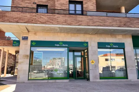 Fachada de Caja rural de Soria con su logo verde y blanco. Se ve un cajero automático y un cartel de "Camino de los Royales".