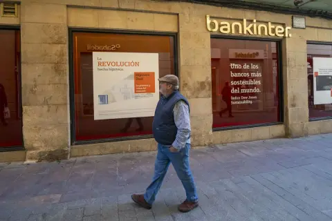 Un hombre camina frente a una sucursal de Bankinter. Las reseñas de Bankinter destacan su compromiso con la sostenibilidad.