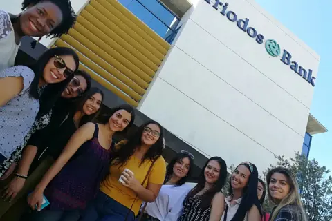 Grupo de amigas sonriendo frente al edificio de Triodos Bank. Sus opiniones sobre el banco son positivas.