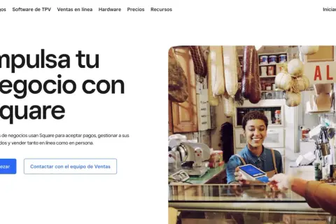 Una mujer sonríe mientras acepta un pago con tarjeta en su tienda, mostrando cómo Square facilita el web e-commerce y las ventas en persona.