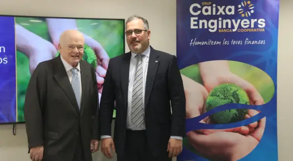 Dos hombres posan frente a un cartel de Caixa Enginyers. Las opiniones sobre la entidad son positivas, destacando su enfoque en "humanizar las finanzas".