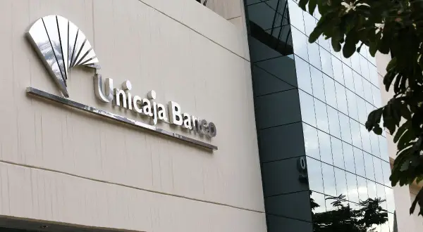 Fachada de Unicaja Banco con su logo metálico. Las reseñas sobre este banco son variadas, pero la imagen muestra su presencia física.