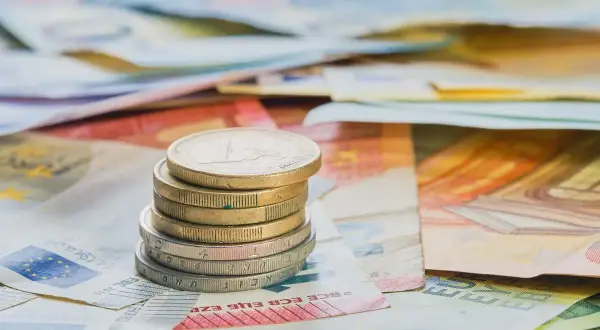 Pila de monedas de euro sobre billetes. Cada moneda cuenta diferentes opiniones sobre el valor del dinero.