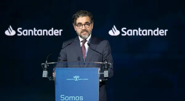 Hombre con traje habla en un congreso. El logo de Santander aparece dos veces. Opiniones sobre Banco Santander.