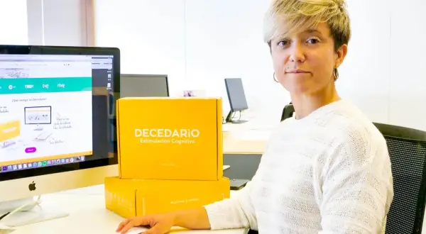 Diana de Arias, rodeada de cajas de "Decedario", un juego para estimulación cognitiva.