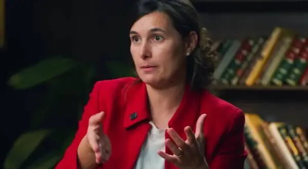 Andrea, del club de inversión, comparte sus opiniones con gestos enfáticos. Detrás, estanterías llenas de libros.