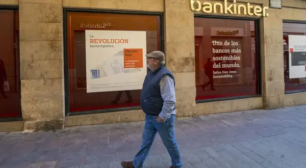 Un hombre camina frente a una sucursal de Bankinter. Las reseñas de Bankinter destacan su compromiso con la sostenibilidad.