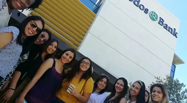 Grupo de amigas sonriendo frente al edificio de Triodos Bank. Sus opiniones sobre el banco son positivas.