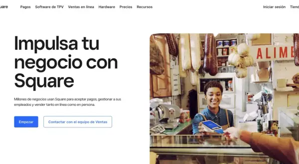 Una mujer sonríe mientras acepta un pago con tarjeta en su tienda, mostrando cómo Square facilita el web e-commerce y las ventas en persona.
