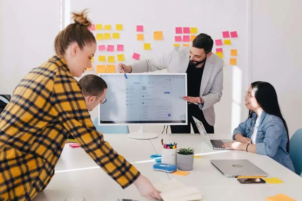 Equipo colaborando en ideas para los mejores negocios online. Un hombre señala la pantalla de un ordenador, mientras otros dos observan.