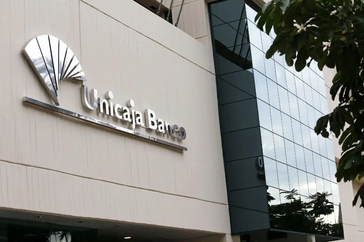 Fachada de Unicaja Banco con su logo metálico. Las reseñas sobre este banco son variadas, pero la imagen muestra su presencia física.