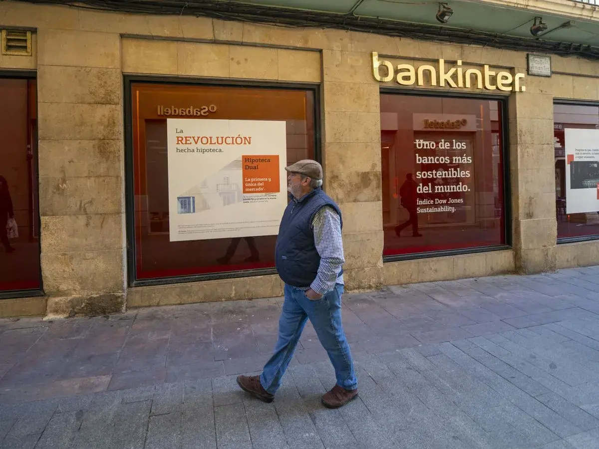 Un hombre camina frente a una sucursal de Bankinter. Las reseñas de Bankinter destacan su compromiso con la sostenibilidad.