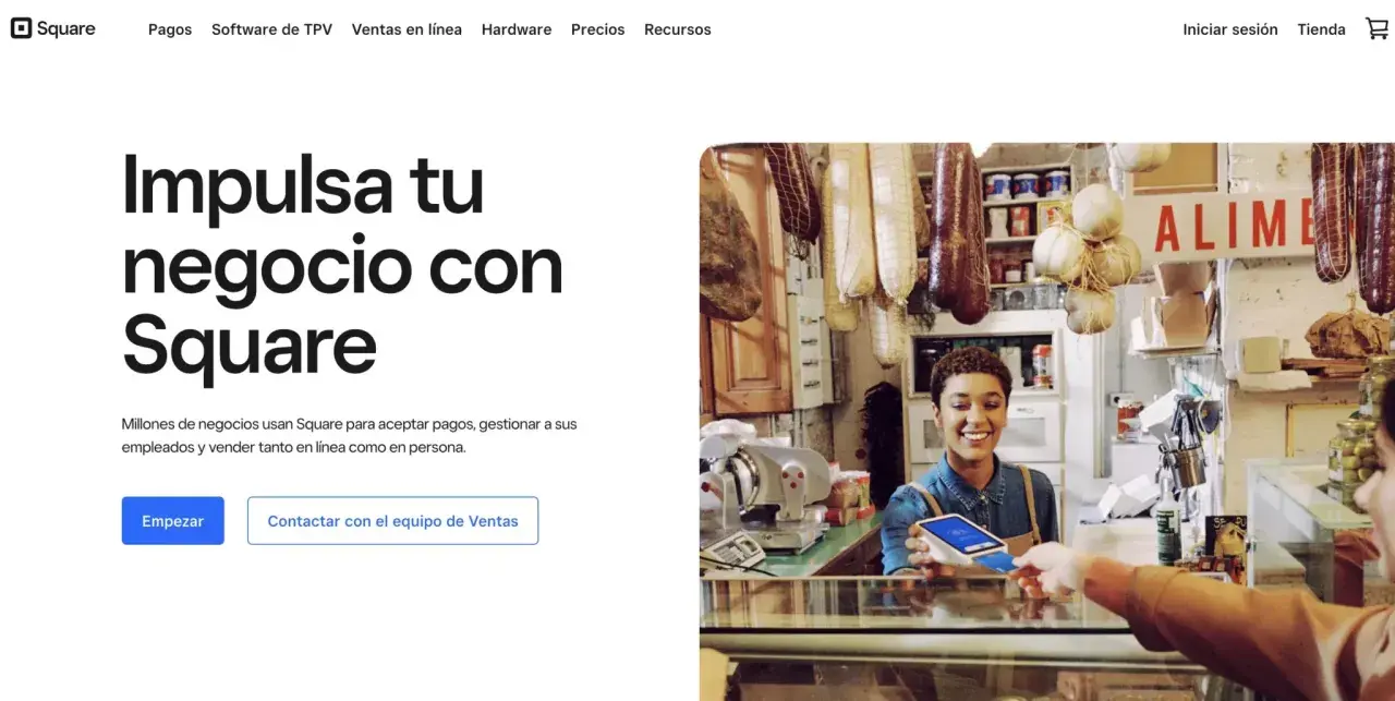 Una mujer sonríe mientras acepta un pago con tarjeta en su tienda, mostrando cómo Square facilita el web e-commerce y las ventas en persona.