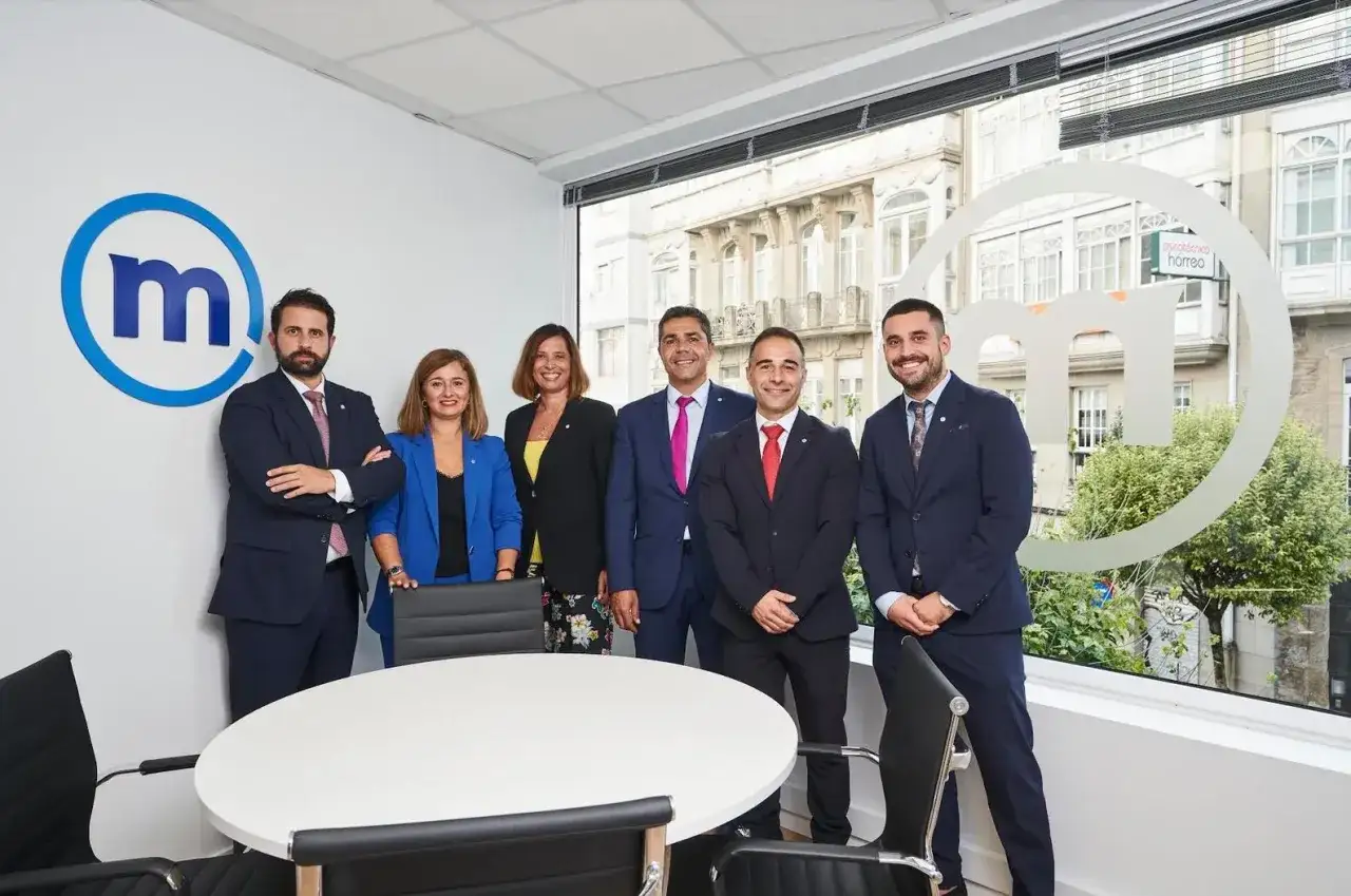 Equipo profesional posando frente al logo de Mediolanum. Buscando banco Mediolanum opiniones, aqu&iacute; tienes un vistazo a su equipo.