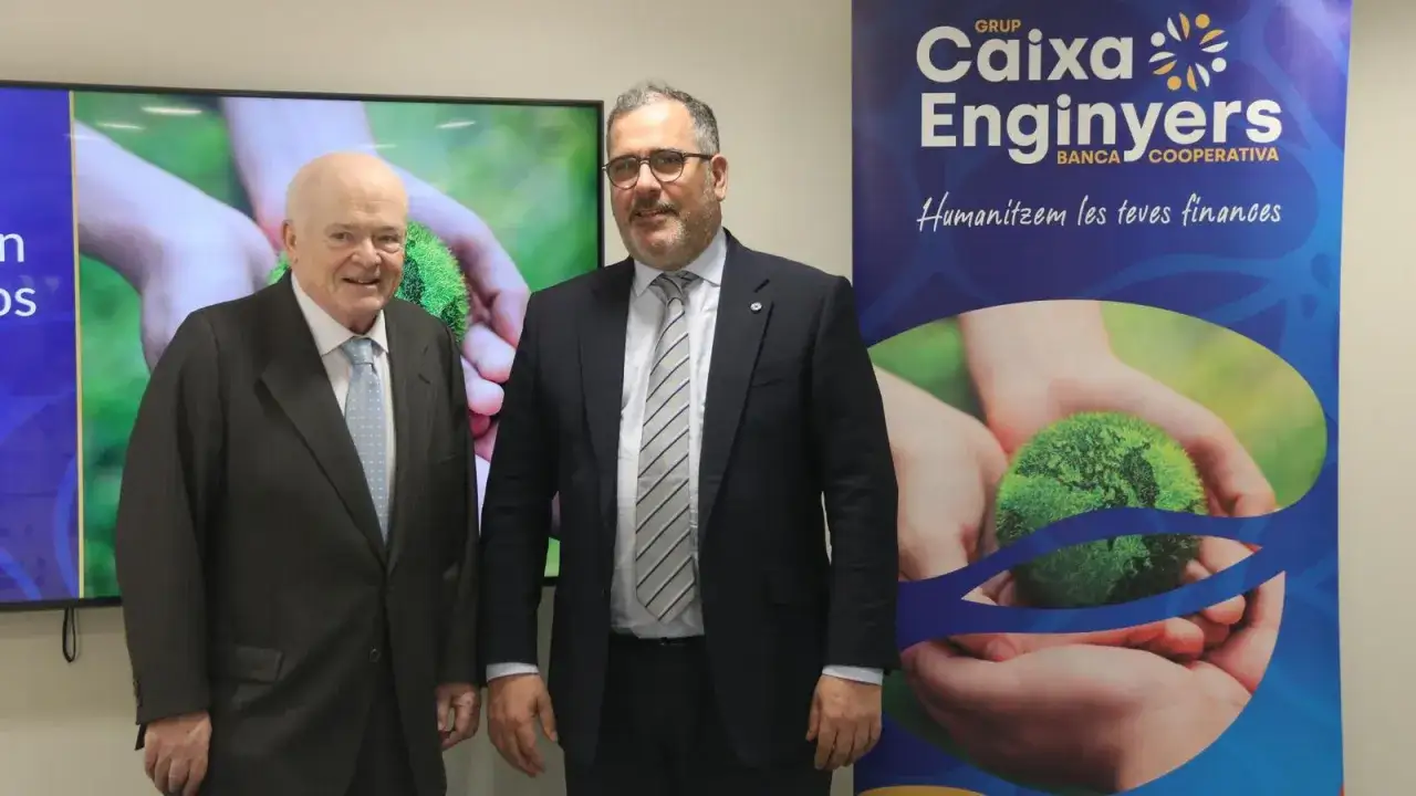 Dos hombres posan frente a un cartel de Caixa Enginyers. Las opiniones sobre la entidad bancaria son positivas, destacando su enfoque en 
