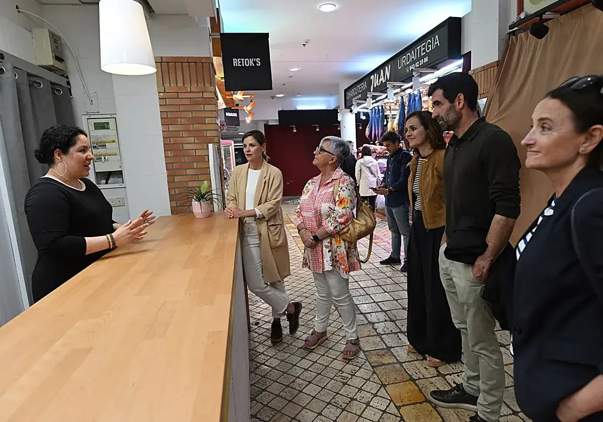 Un grupo de personas escucha atentamente mientras una mujer explica c&oacute;mo crear una comunidad en un mercado local.