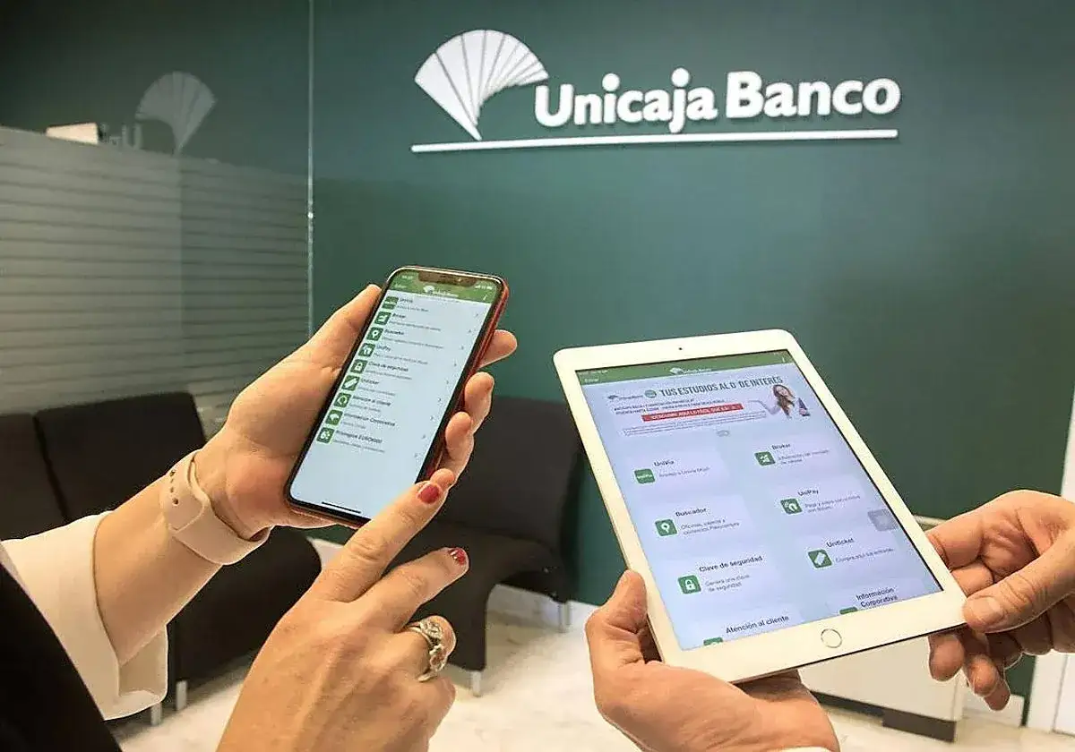 Manos sostienen un m&oacute;vil y una tablet mostrando la app de Unicaja Banco, ideal para consultar rese&ntilde;as y gestiones.