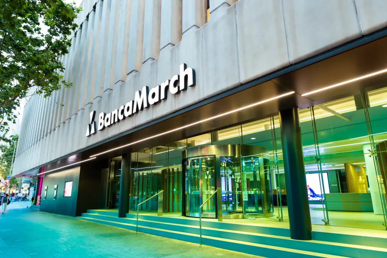 Fachada moderna de Banca March con su logo iluminado. Las opiniones sobre Banca March suelen destacar su servicio personalizado.