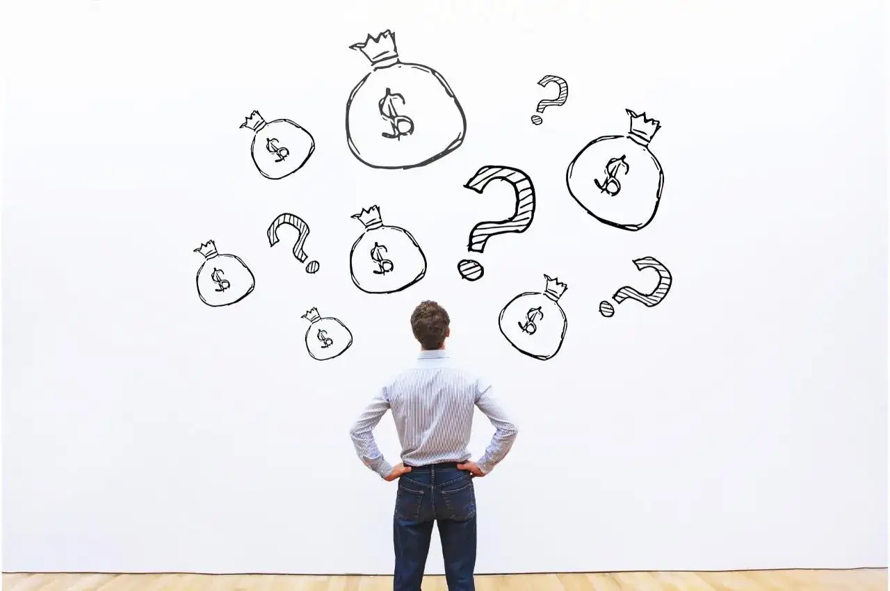 Hombre frente a bolsas de dinero y signos de interrogaci&oacute;n, pensando c&oacute;mo ganar dinero con las acciones.