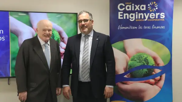 Dos hombres posan frente a un cartel de Caixa Enginyers. Las opiniones sobre la entidad son positivas, destacando su enfoque en "humanizar las finanzas".
