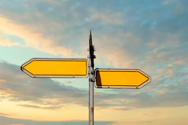 Doble señalización amarilla vacía, como **leading indicators** de un camino a seguir, contra un cielo nublado.