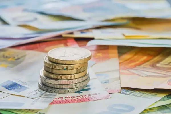 Pila de monedas de euro sobre billetes. Cada moneda cuenta diferentes opiniones sobre el valor del dinero.