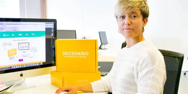 Diana de Arias, rodeada de cajas de "Decedario", un juego para estimulación cognitiva.