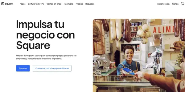 Una mujer sonríe mientras acepta un pago con tarjeta en su tienda, mostrando cómo Square facilita el web e-commerce y las ventas en persona.
